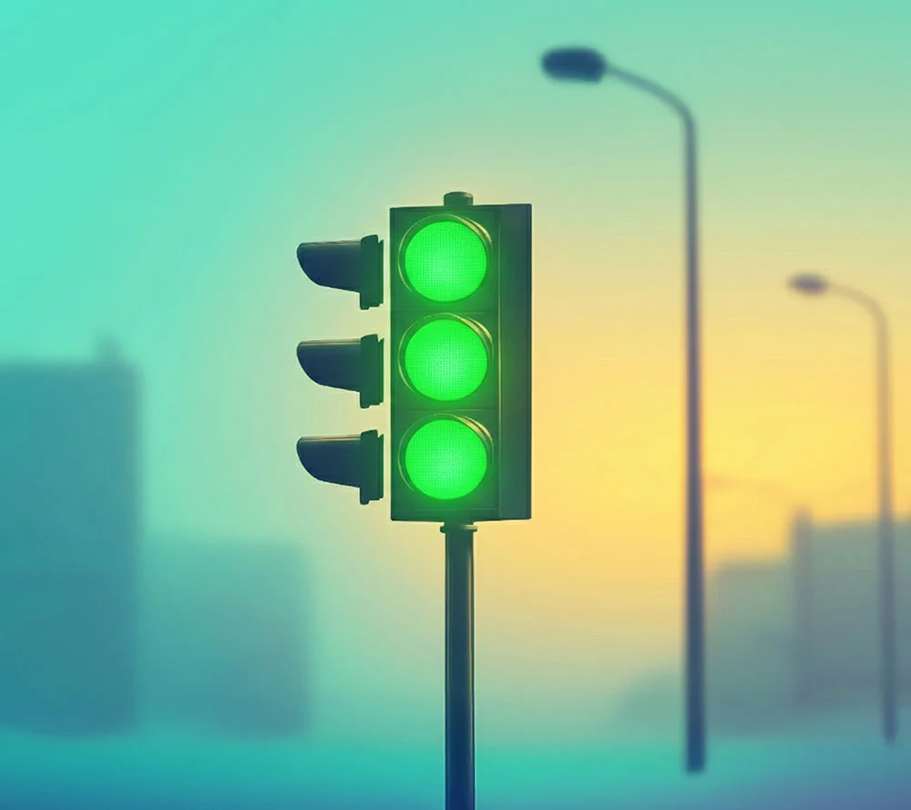 Green traffic light glowing against a blurred city street at sunset