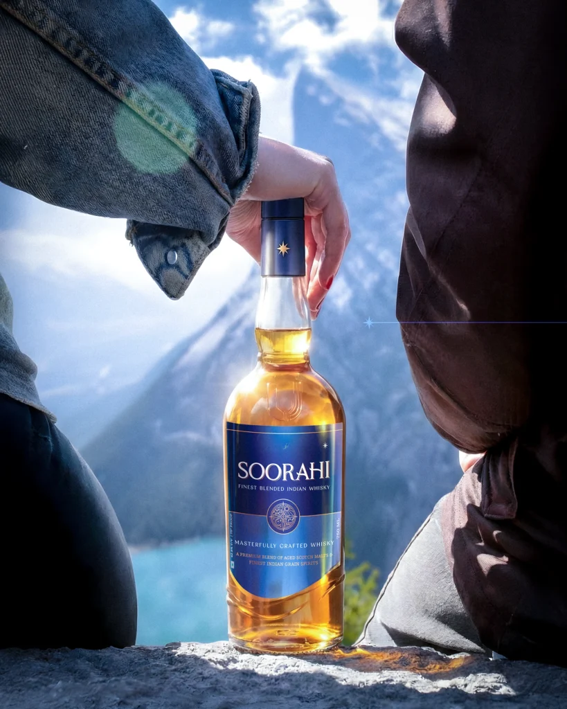 Soorahi premium Indian whisky bottle displayed outdoors with mountain scenery